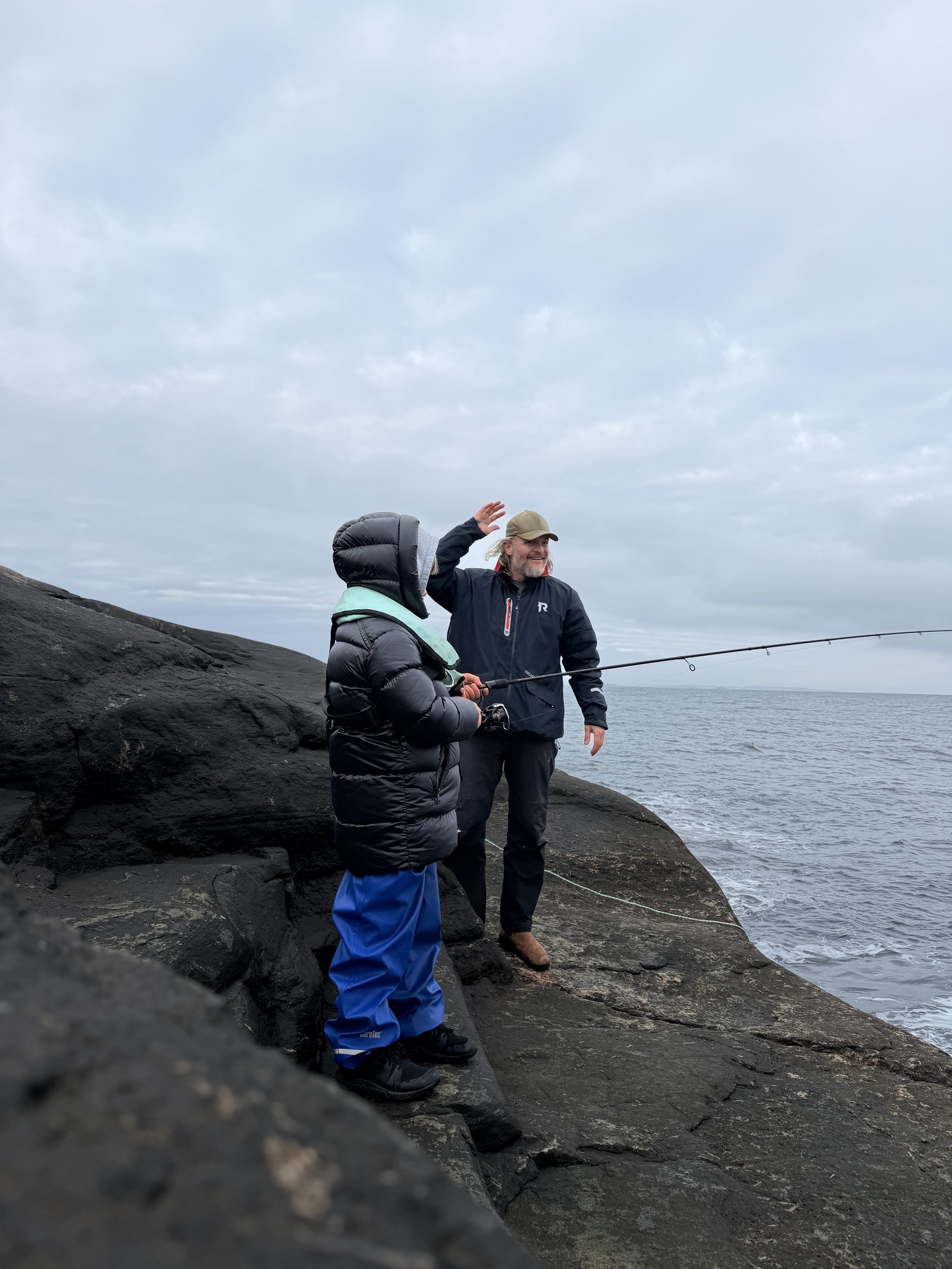 A father and child fishing together on the coastal rocks of the Søgne Archipelago